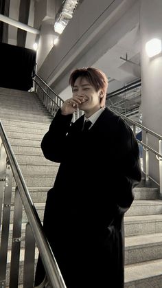 a man standing on the stairs talking on his cell phone while wearing a suit and tie