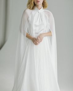 a woman in a white dress and cape