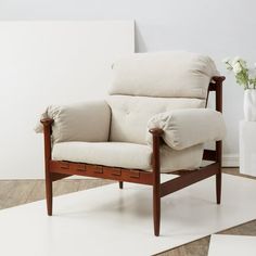 a white chair sitting on top of a wooden floor next to a vase with flowers