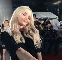 a woman with long blonde hair standing in front of a camera