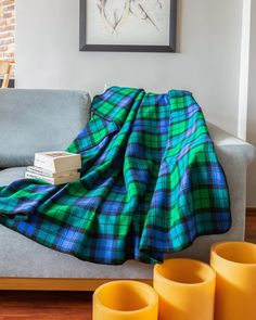 a plaid blanket sitting on top of a couch next to yellow vases and cups