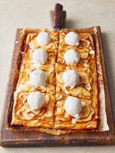 an apple tart topped with ice cream on top of a wooden cutting board next to a knife