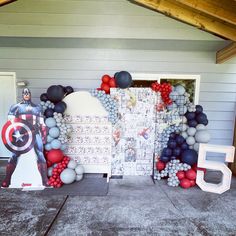 some balloons are on the ground near a door and captain america is standing in front of it