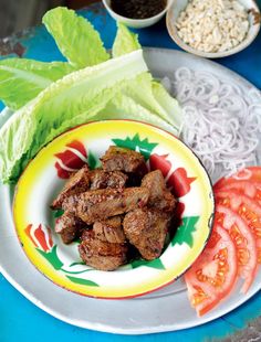 a plate with meat, tomatoes and lettuce on it next to other foods