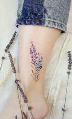 a woman's foot with purple flowers on it and some lavenders in the foreground