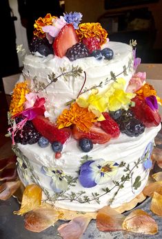 a multi layer cake decorated with fresh fruit and flowers