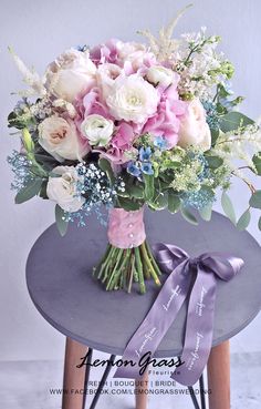 a bouquet of flowers sitting on top of a table next to a purple ribbon tied around it