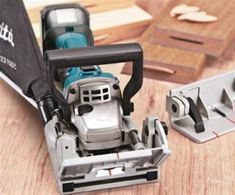 a sanding machine sitting on top of a wooden table next to a piece of wood