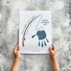 two hands holding up a fathers day card with a handprinted image of a father's hand