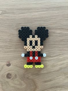 a mickey mouse beaded brooch sitting on top of a wooden table