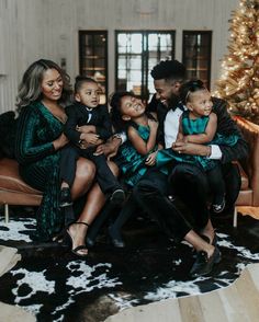 a family sitting on a couch in front of a christmas tree