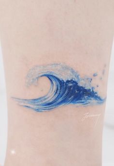 a blue wave tattoo on the side of a woman's lower leg is shown