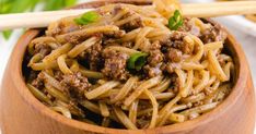 a wooden bowl filled with noodles and meat