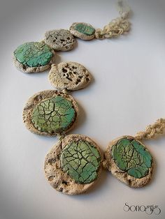 a necklace made out of rocks with green and white designs on it's sides