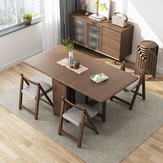 a dining room table with chairs and a vase on the top, in front of a window