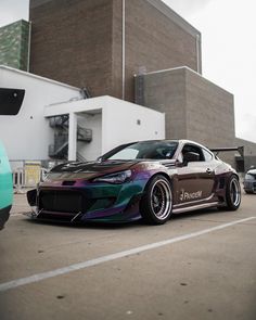 a car parked in a parking lot next to a building and another car behind it