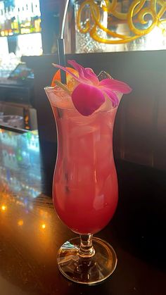 a pink drink in a tall glass on a bar