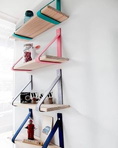 three shelves with various items on them against a white wall in the corner of a room