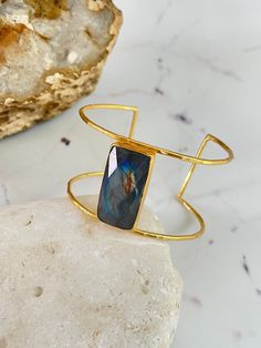 21 ct gold plated brass. Labradorite semi-precious stone Free size - Due to natural stone, the color and pattern are one by one unique.  It can be little bit differ from the pictures. There might be cracks and dot by natural Designed by our Turkish designer. Handcrafted with great care. Gold Cuff Bracelet With Natural Stones, Gold Labradorite Bracelet As Gift, Brass Bracelet With Natural Stones, Adjustable Labradorite Cuff Bracelet As Gift, Unique Labradorite Bangle Jewelry, Silver Labradorite Bangle Bracelet, Bohemian Gold Labradorite Bracelet, Hand-strung Labradorite Beaded Bracelets As Gift, Bangle Gold