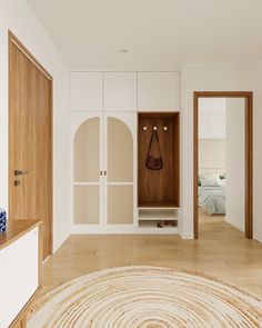 an empty room with white walls and wooden furniture, including a large round rug on the floor