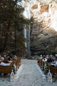 an outdoor ceremony with people sitting in wooden pews