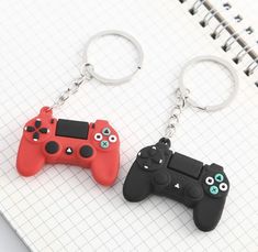 two video game controllers key chains on top of a notepad next to each other