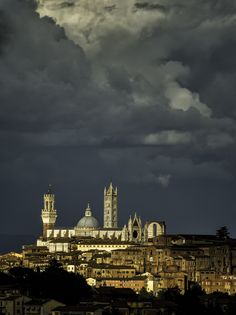 the clouds are dark and cloudy over an old city