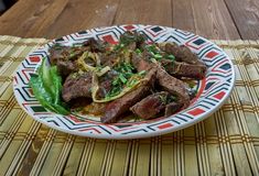 a white plate topped with meat and veggies on top of a wooden table