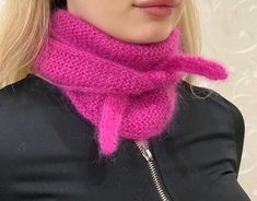 a woman with blonde hair wearing a pink knitted cowl neck scarf and black jacket