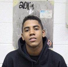 a young man standing in front of a wall with graffiti on it's side