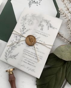 a wedding card with a wax stamp on it next to some leaves and foliages