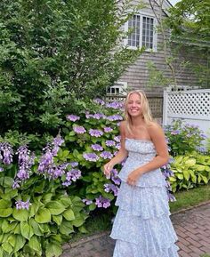 a woman standing in front of purple flowers