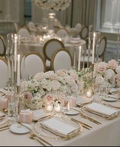 the table is set with white and pink flowers, candles, and place settings for dinner