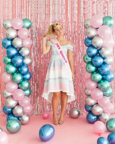 a woman standing in front of balloons and streamers