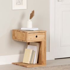 a small wooden table with books and a vase on it next to a white door