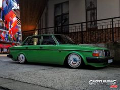 a green car parked in front of a tall building