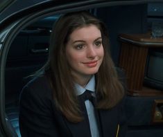 a woman wearing a suit and tie sitting in a car