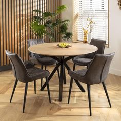 a round dining table with four chairs around it in a room that has wood flooring