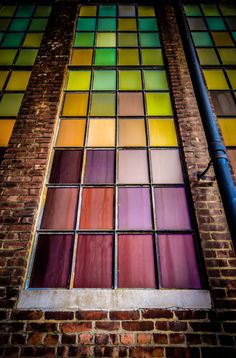 a multicolored stained glass window on the side of a brick building