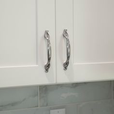 a kitchen with white cabinets and marble counter tops, two handles on the cabinet doors