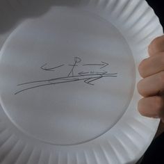 a person holding a paper plate with a drawing on it