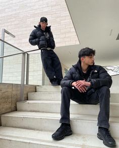 two men sitting on the steps in front of a building