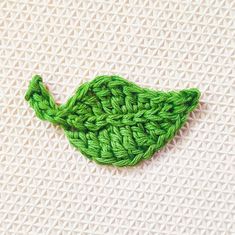 a green crocheted leaf on a white surface