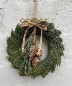 a pine cone and twine wreath hanging on a wall with two small pine cones