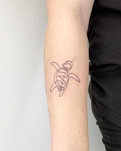 a woman's arm with a small turtle tattoo on the left side of her arm