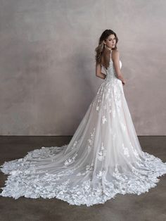 a woman in a white wedding dress with flowers on the skirt is standing against a wall