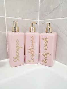 three pink soap dispensers with gold lettering on them