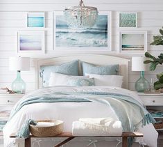 a bedroom with white walls and pictures on the wall above the bed, along with a chandelier