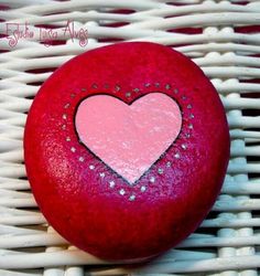 a red rock with a heart painted on it sitting on a wicker tablecloth