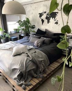 an instagram photo of a bed in a room with plants on the floor and a world map above it